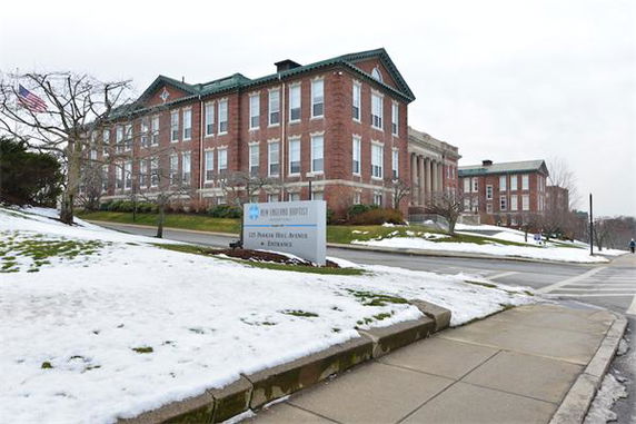 Front view of a large, multi-story brick building with numerous windows.