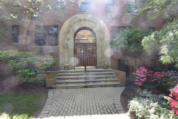 Front view of a brick building with an arched entrance and steps.