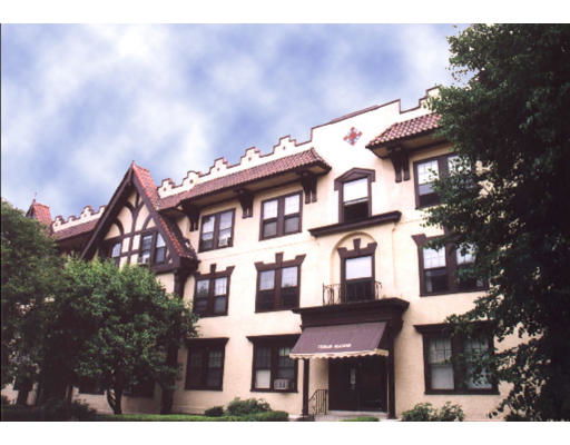 Front view of a three-story building with decorative roof design and prominent windows.