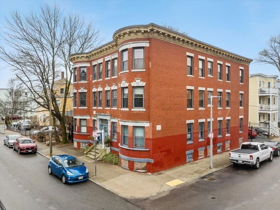 Front view of a three-story brick building on a street corner.
