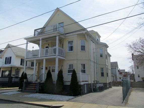 Front view of a multi-story house with balconies and a gabled roof.