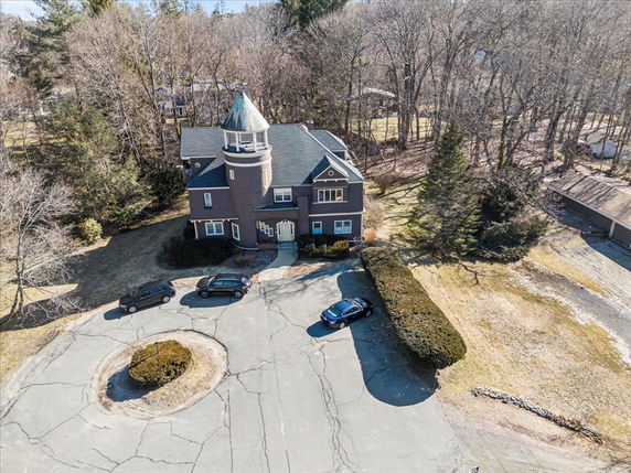 Front view of a house with a round tower and multiple vehicles parked in front.