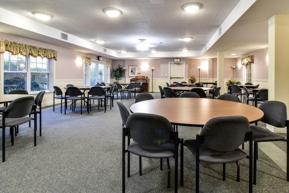 Room with multiple round tables and chairs for meetings or social gatherings.