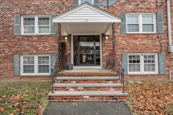 Front view of a brick apartment building with multiple windows and a small entrance porch.