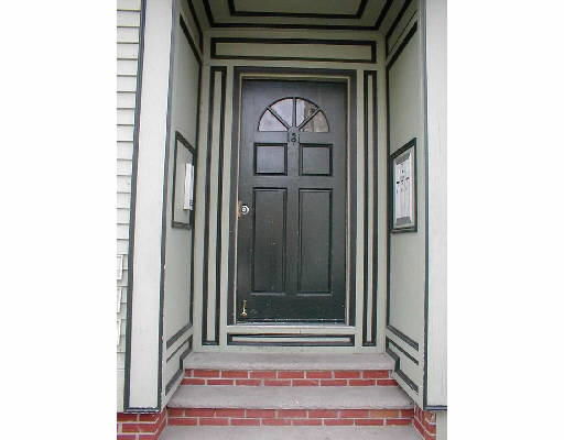 Front view of a door with decorative trim and brick steps leading up to it.