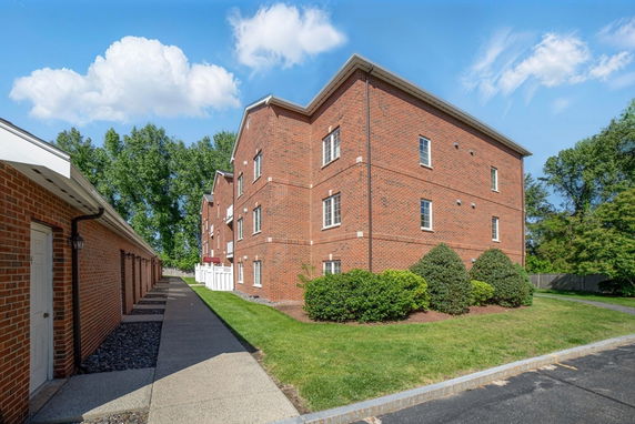Side view of a three-story brick apartment building with multiple windows.