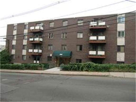 Front view of a multi-story brick apartment building with balconies.