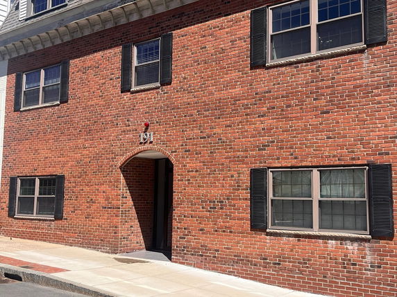 Front view of a brick building with multiple windows and a single entrance.