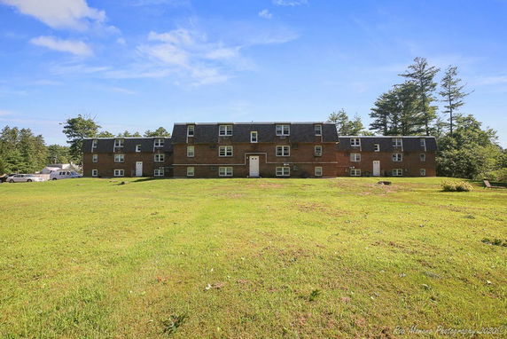 Front view of a large multi-story brick building with numerous windows and gabled roofs.