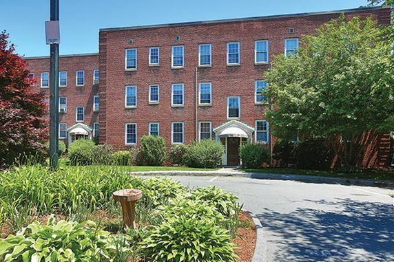 Front view of a three-story brick building with symmetrical windows and entrance awnings.