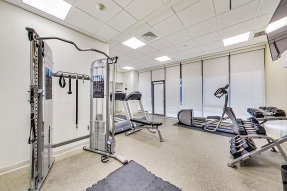 Indoor gym area with exercise equipment and weights.