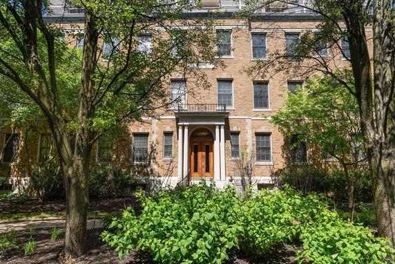 Front view of a multi-story brick building with columns at the entrance.
