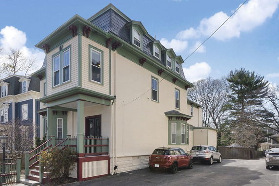 Front view of a multi-story house with decorative trim and mansard roof.