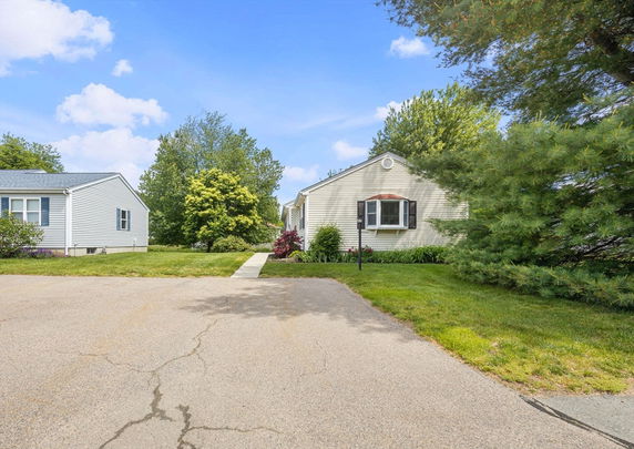 Front view of a single-story house with a paved driveway and garden.