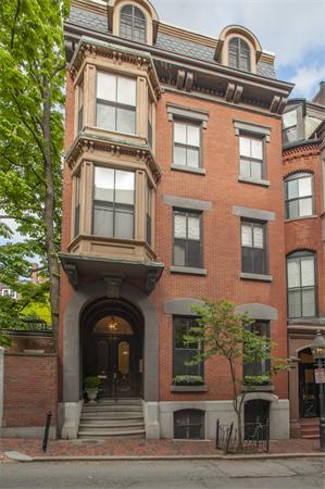 Front view of a multi-story brick building with bay windows and arched doorway.