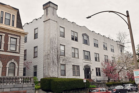 Front view of a multi-story building with a light facade and several windows.