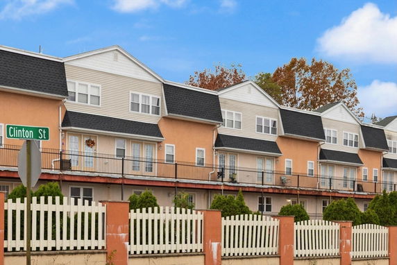 Front view of a multi-story residential building with a white picket fence.