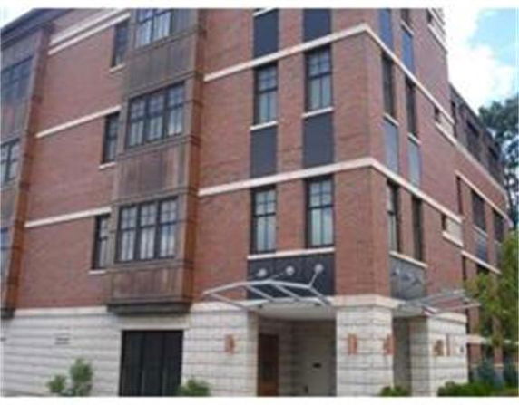 Front view of a multi-story brick building with large windows and a metal entrance canopy.