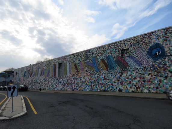Front view of a long building with a colorful mural on the wall.