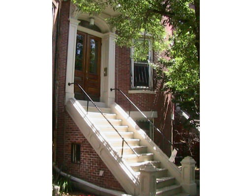 Front view of a brick house with a staircase leading to the entrance.