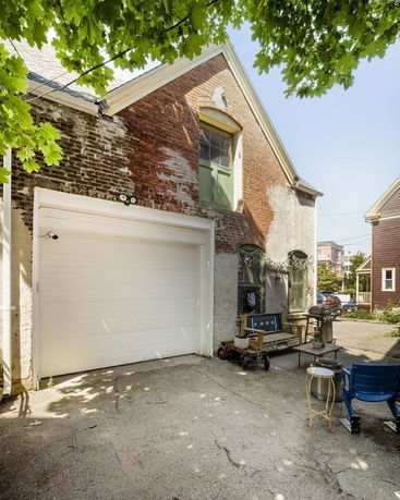 Front view of a two-story house with a garage in exposed brick and stucco finish.
