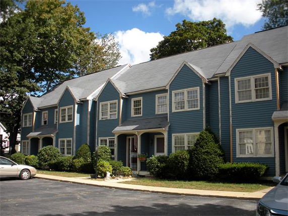 Front view of a multi-story residential building with blue siding and multiple gabled roofs.