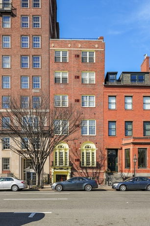 Front view of a multi-story brick building with large windows and decorative yellow accents around the entrance.