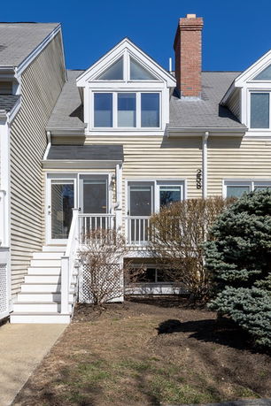 Front view of a two-story house with a gable roof and a chimney, featuring triangular windows on the upper floor.