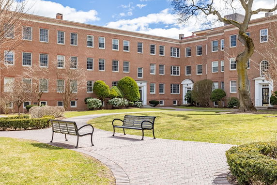 Front view of a large, multi-story brick building with numerous windows and arched doorways.