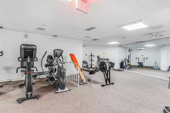 Indoor gym area with exercise equipment and mirrored wall.