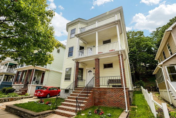Front view of a three-story house with a brick porch and balconies.