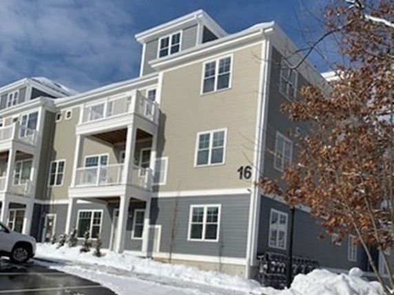 Front view of a multi-story building with balconies and snow around the premises.