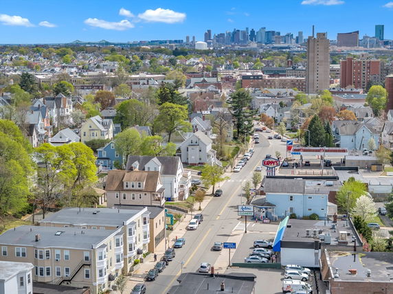 Panoramic view of a residential neighborhood with buildings and distant city skyline.