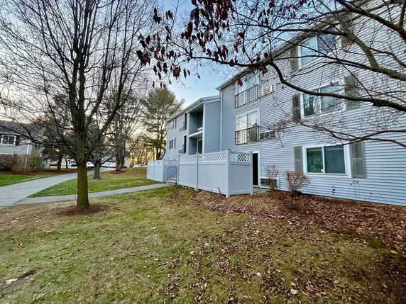 Front view of a multi-story residential building with balconies and a pathway.