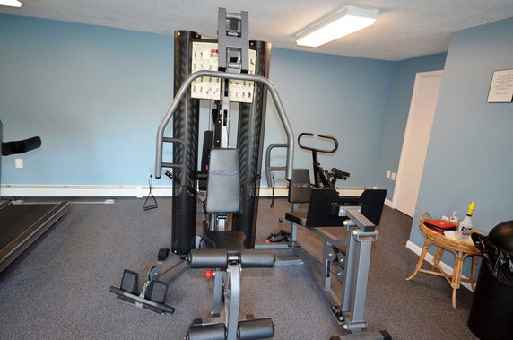 Indoor gym with exercise equipment and a blue wall.