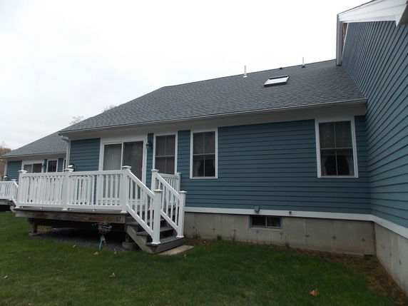 Front view of a single-story house with a grey roof and a white railing porch.