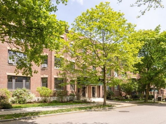 Front view of a multi-story brick building with trees in front.