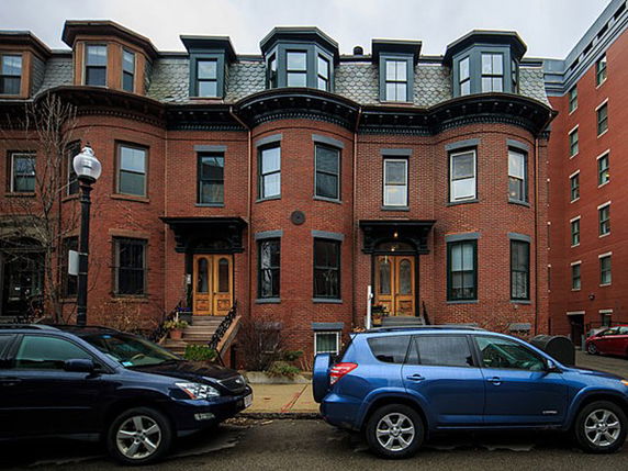 Front view of a multi-story brick townhouse with bay windows.