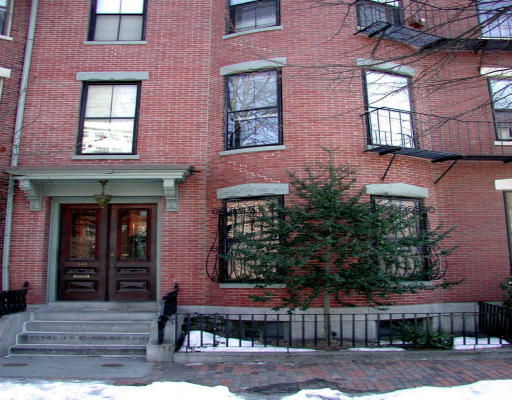 Front view of a multi-story brick building with fire escapes.