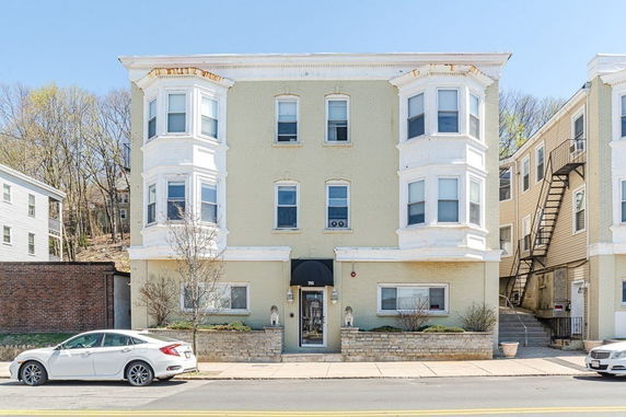 Front view of a three-story building with two bay windows and an entrance canopy.