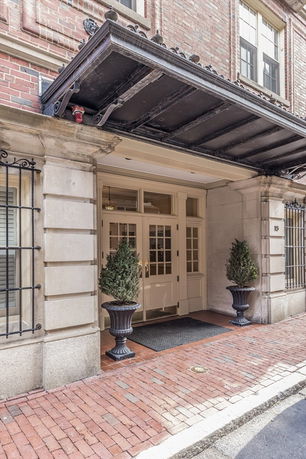 Front view of a building entrance with an overhang and potted plants.