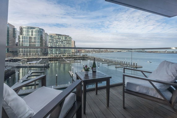 Panoramic view from a balcony overlooking a marina with modern buildings and expansive water body.