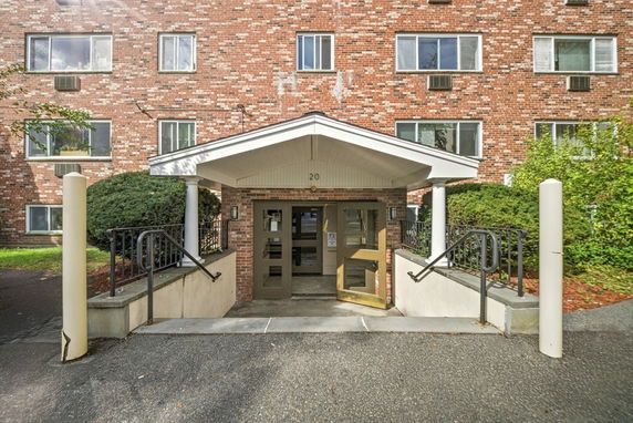 Front view of a multi-story brick building entrance with stairs and a small canopy.