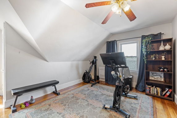 Interior room with exercise equipment, including a bench and stationary bike, under sloped ceiling.