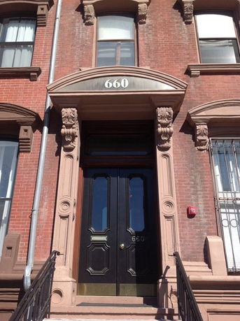 Front view of a brick building with ornate door and windows.