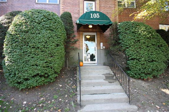 Entrance of a brick building with a green awning and number 105.