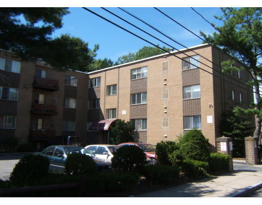 Front view of a multi-story brick apartment building with parking area in front.