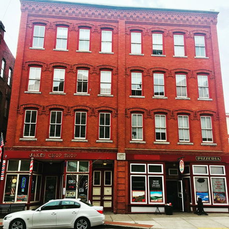 Front view of a multi-story red brick building with storefronts on the ground floor.