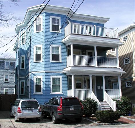 Front view of a three-story blue house with balconies and white trim.