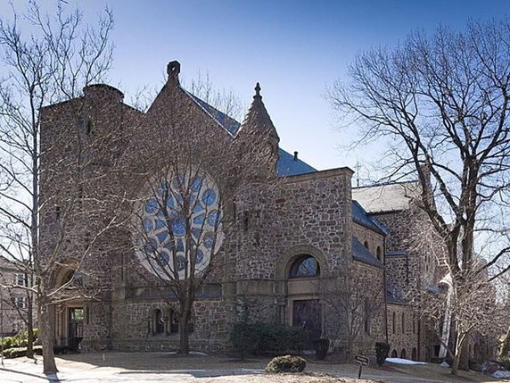 Front view of a historic stone building with large, circular stained glass window.